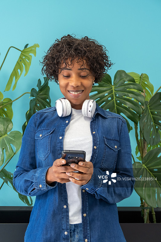 年轻的非洲裔黑人女子手持智能手机，使用手机APP进行电商购物或观看视频图片素材