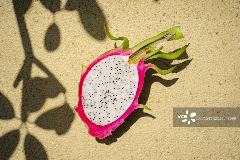 阳光明媚的黄色背景下，切成两半的火龙果特写图片素材