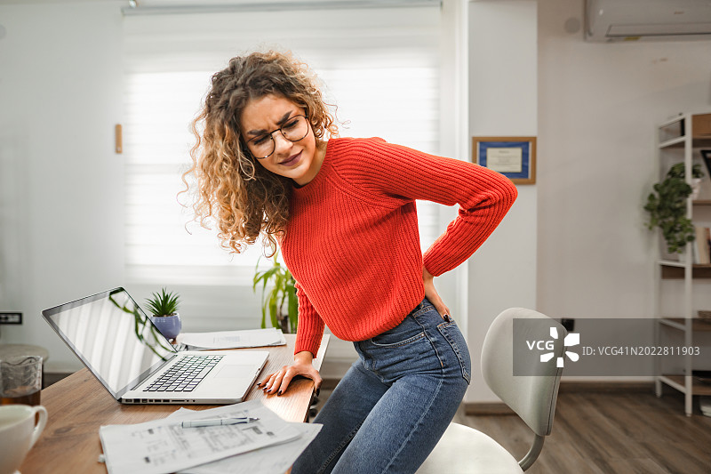 白人女性在办公桌前工作时背痛图片素材
