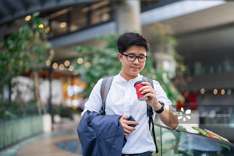 商人拿着智能手机和咖啡杯在外面咧嘴笑图片素材