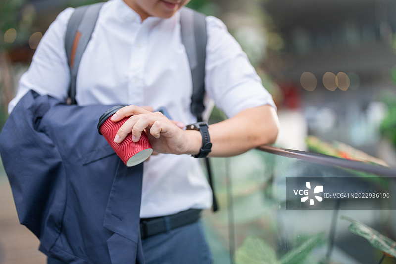 商人拿着智能手机和咖啡杯在外面咧嘴笑图片素材