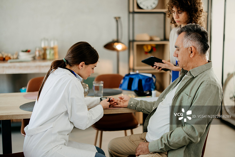 医生在家中为老年患者检查血糖图片素材