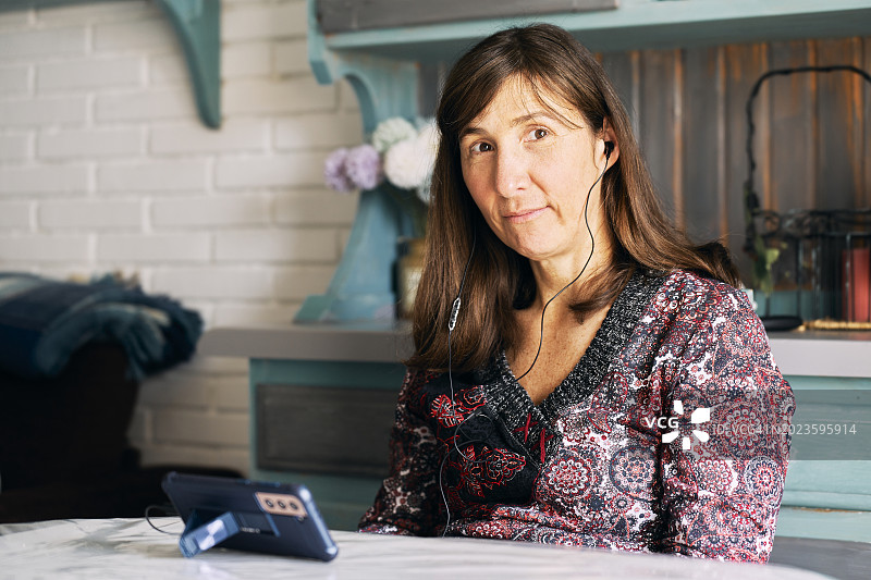 在客厅里用耳机听音乐的休闲女人图片素材