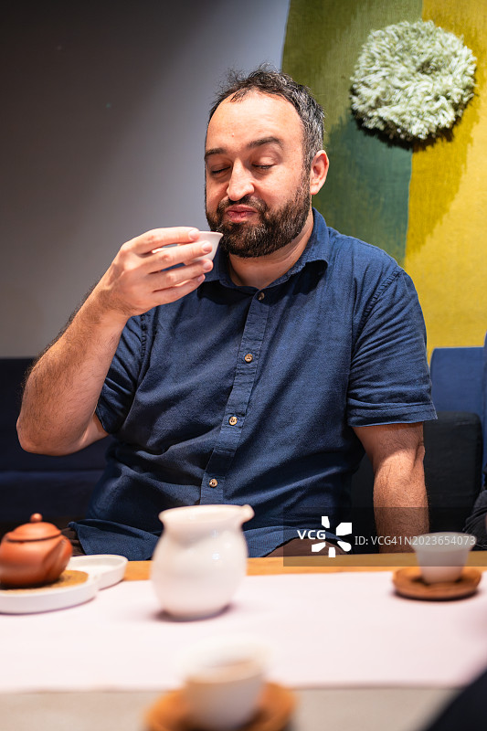 专家在小瓷碗中品味饮品，闭着眼睛，参加中国台湾茶道图片素材