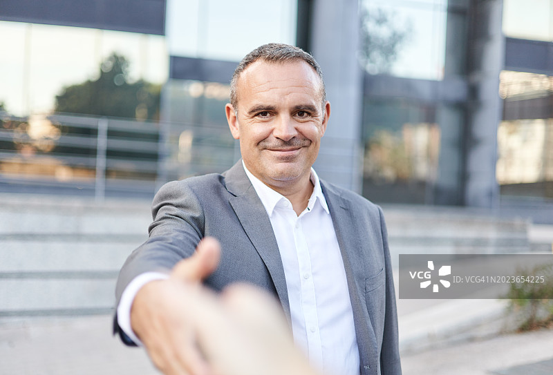 年长的商人在街上问候合作伙伴图片素材