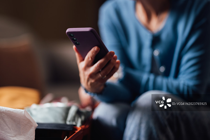 年轻人使用智能手机，焦点在打包好的手提箱上图片素材