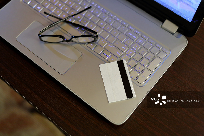 笔记本电脑和信用卡高空景观，键盘上有眼镜图片素材