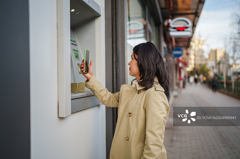 用手机从ATM取款的亚洲女性图片素材