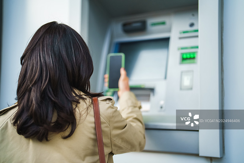 系列：亚洲女人在自动取款机上使用手机图片素材