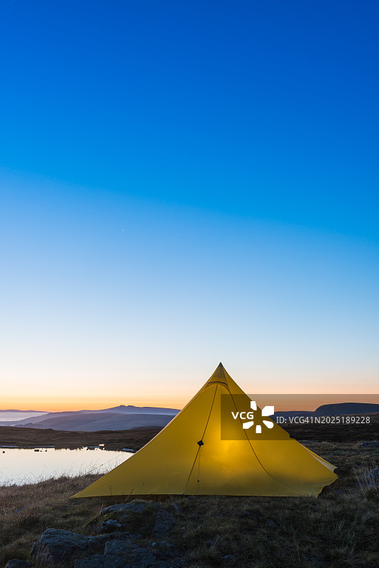 威尔士山湖边在日出时被照亮的彩色帐篷图片素材