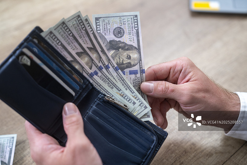 手持少量美元钱包特写图片素材