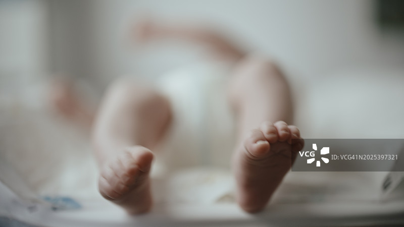 婴儿躺在婴儿床上的腿部特写镜头图片素材