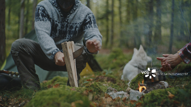 男人砍柴，女人在森林里篝火旁取暖图片素材