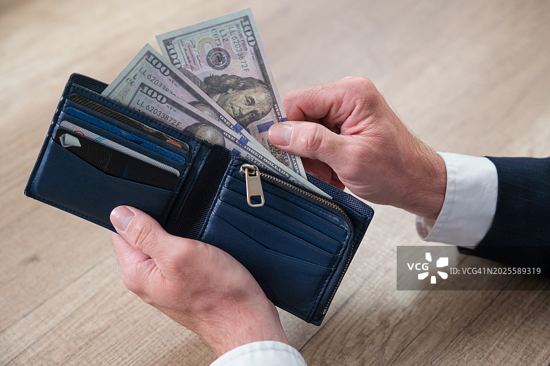 男子手持钱包和美元纸币图片素材