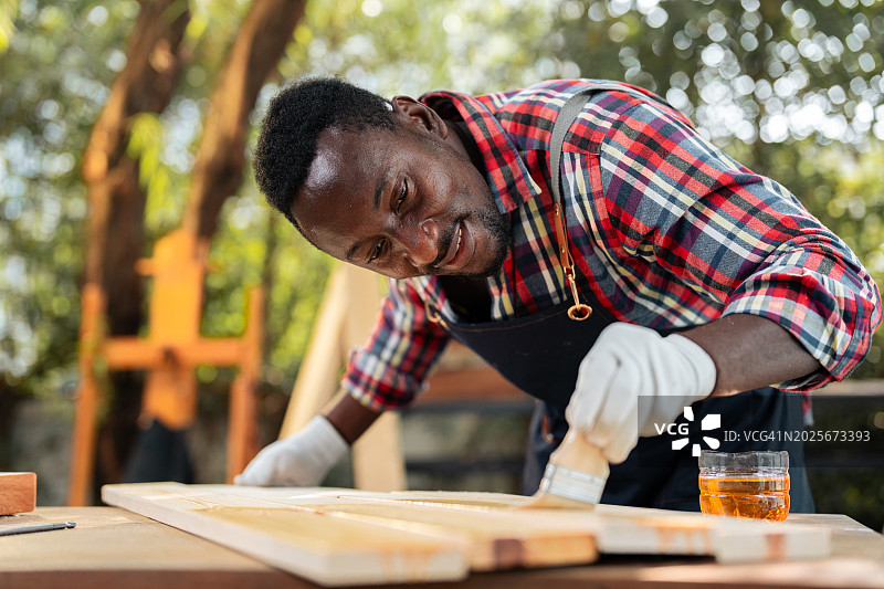 木工车间里在木板上涂油漆或清漆的特写图片素材