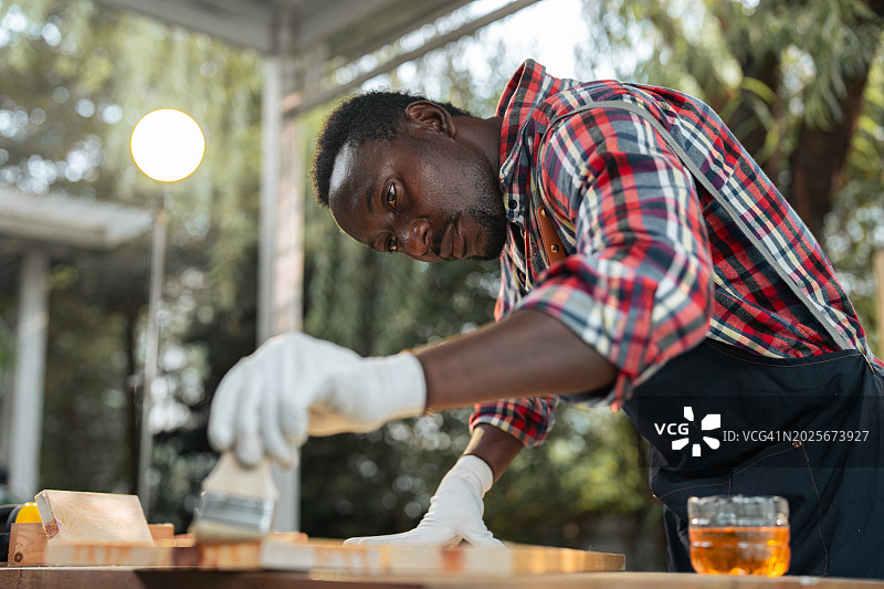 木工车间里在木板上涂油漆或清漆的特写图片素材