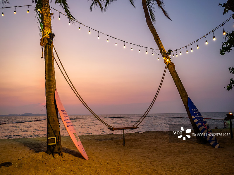 泰国海滩海湾美丽的日落，远处有棕榈树和大海图片素材