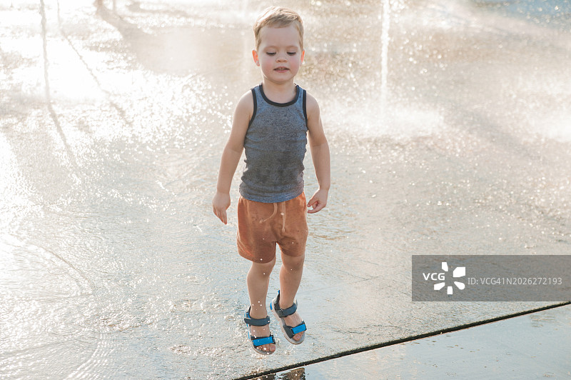3岁儿童在夏日喷泉中嬉戏玩耍图片素材
