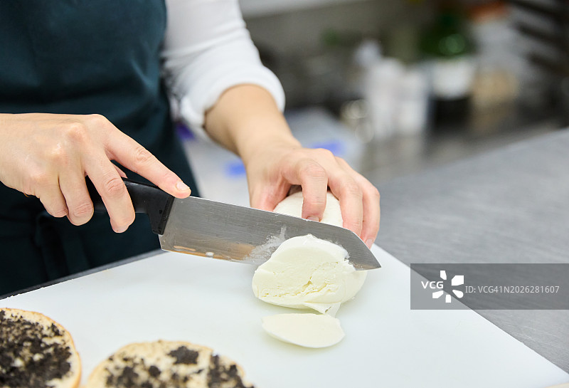 女厨师在面包店厨房准备松露三明治，切马苏里拉奶酪特写图片素材
