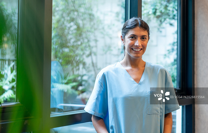 站在医院走廊里对着镜头微笑的女实习医生图片素材