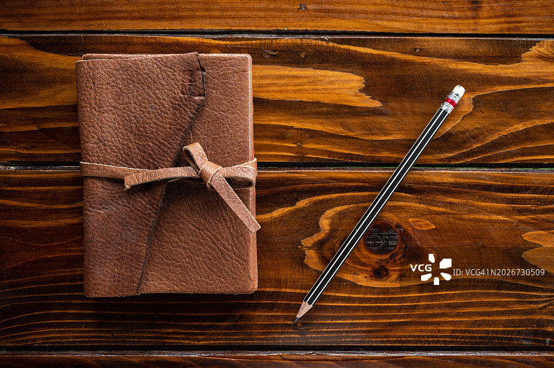 木桌上的皮革日记本和铅笔图片素材
