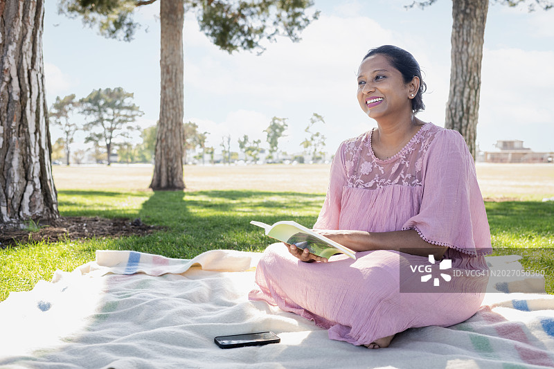 中年妇女在户外毯子上放松阅读图片素材