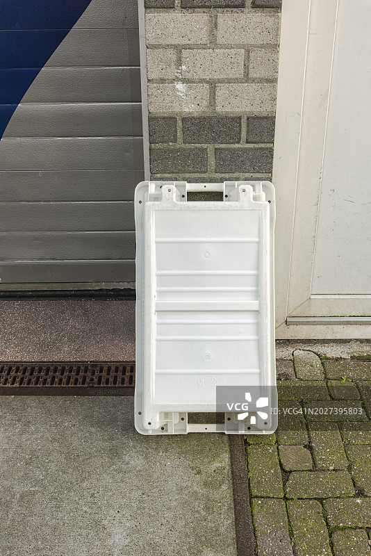 靠石墙放置的白色塑料渔具箱图片素材