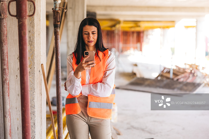 年轻女建筑师在建筑工地使用手机图片素材