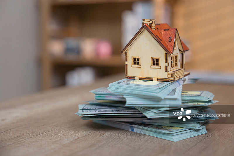 成捆美元纸币上的房屋模型，房地产概念图片素材