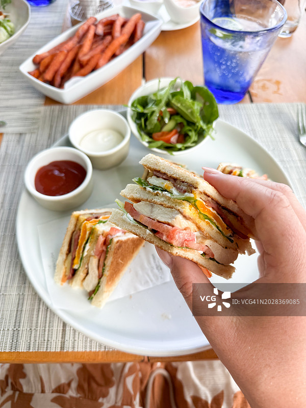 女人在酒店餐厅吃鸡肉俱乐部三明治图片素材