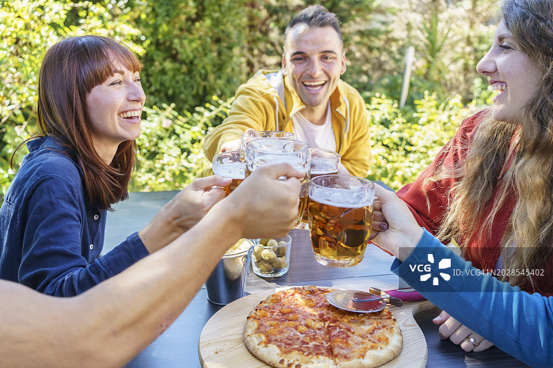年轻的朋友在啤酒厂酒吧花园外面喝酒碰杯图片素材