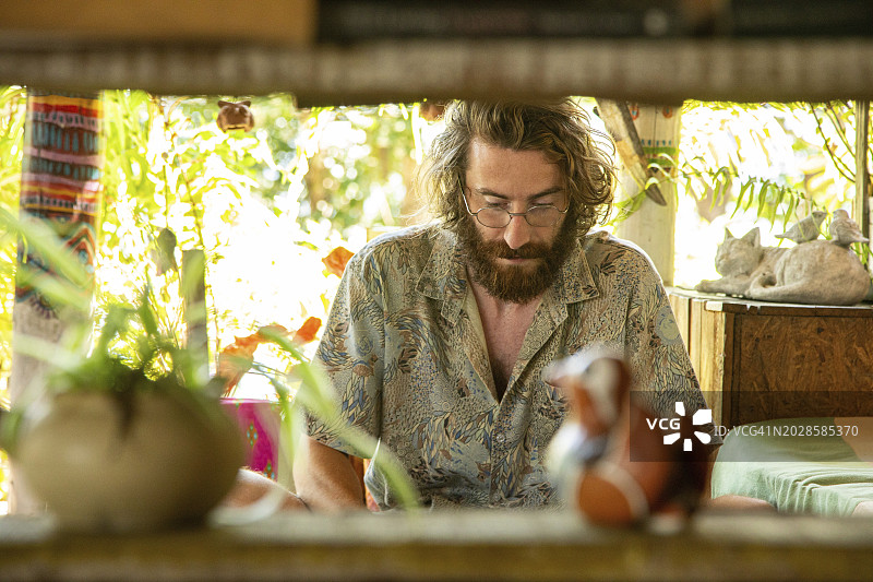 在泰国北部餐厅用笔记本电脑和手机工作的年轻男人图片素材