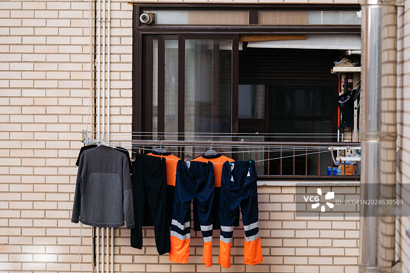 砖墙前阳台栏杆上挂着的工作服图片素材