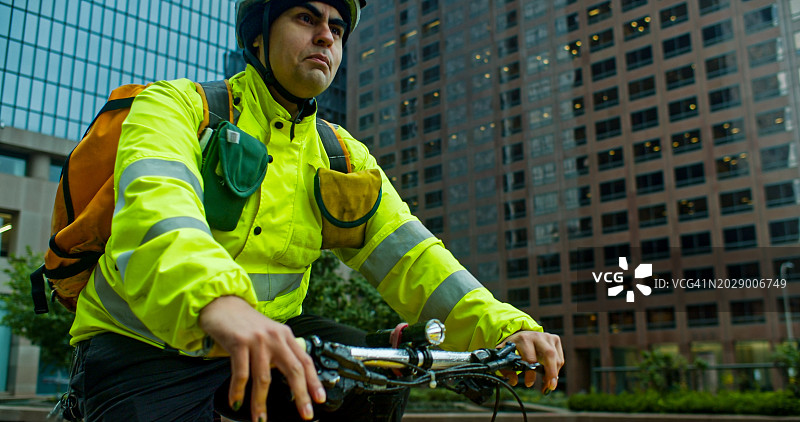 在洛杉矶市中心骑自行车的高可见度送货员 - 中景图片素材