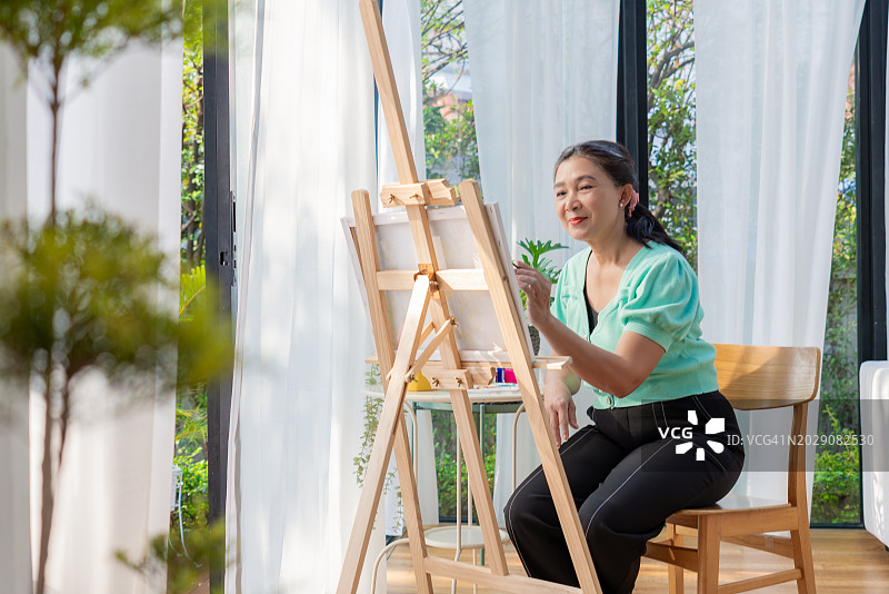 周末在家中客厅绘画的中国退休妇女图片素材