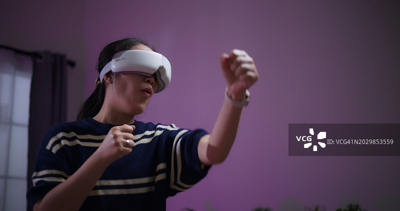 年轻女人在家享受虚拟现实游戏图片素材
