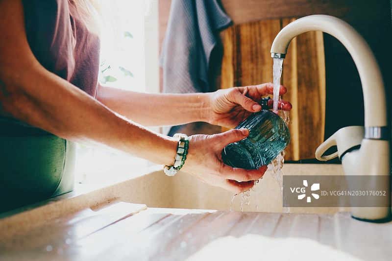 在厨房水龙头下用带纹理的绿色玻璃洗手图片素材