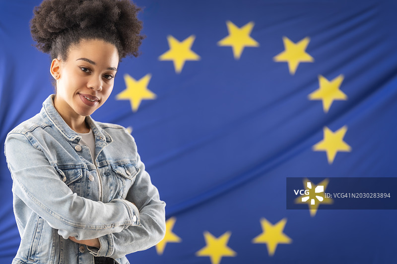 非裔美国女学生站在欧盟旗帜前，双臂交叉图片素材