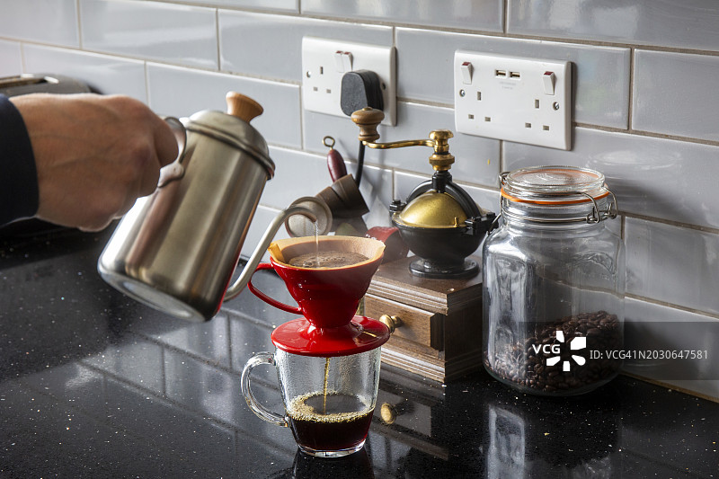 用细嘴壶将水倒入红色咖啡滤杯中制作咖啡图片素材