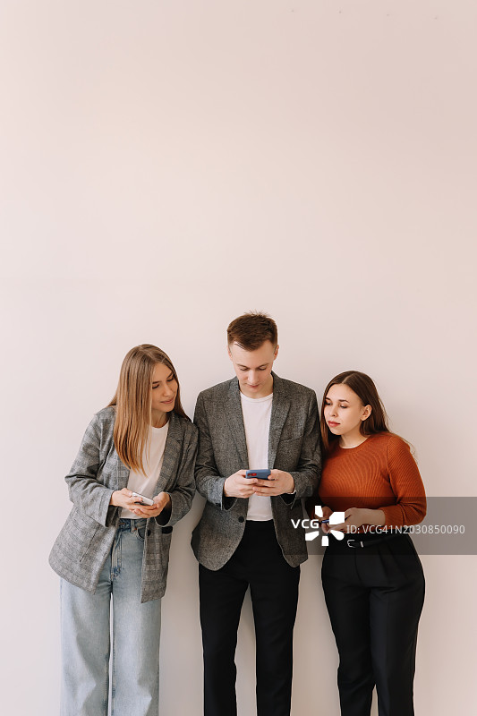 一群身着商务装的同事使用科技产品和智能手机在白色背景前交流工作图片素材