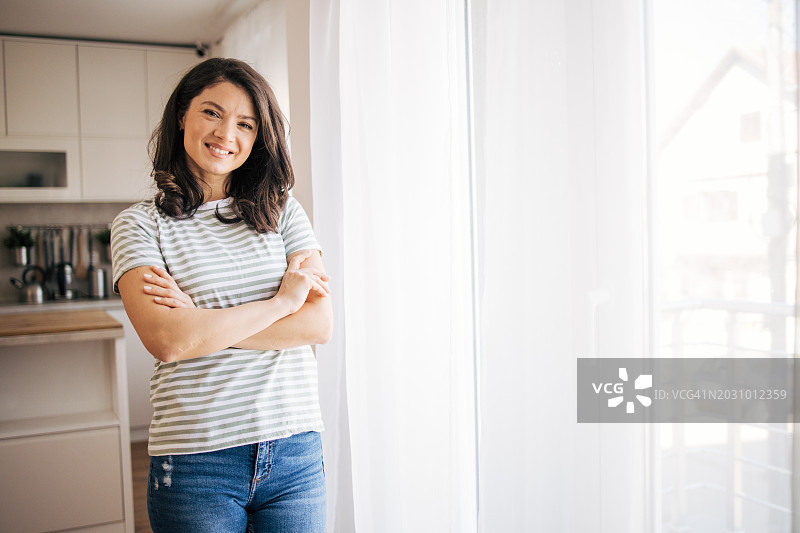 在厨房里双臂交叉的年轻女人图片素材