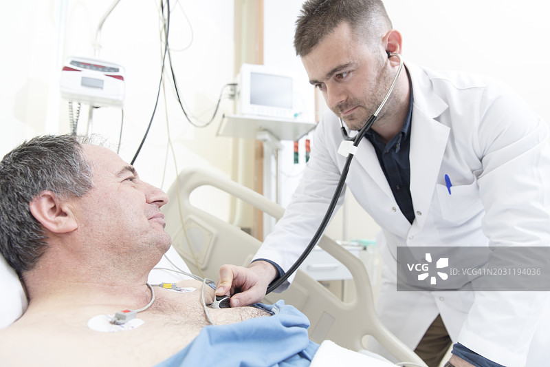 男医生在急诊室用听诊器听老年男病人的心脏图片素材