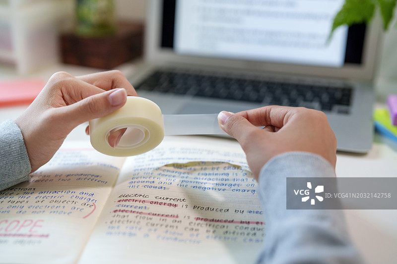 亚洲少女用3M思高魔术胶带修复笔记本页面图片素材