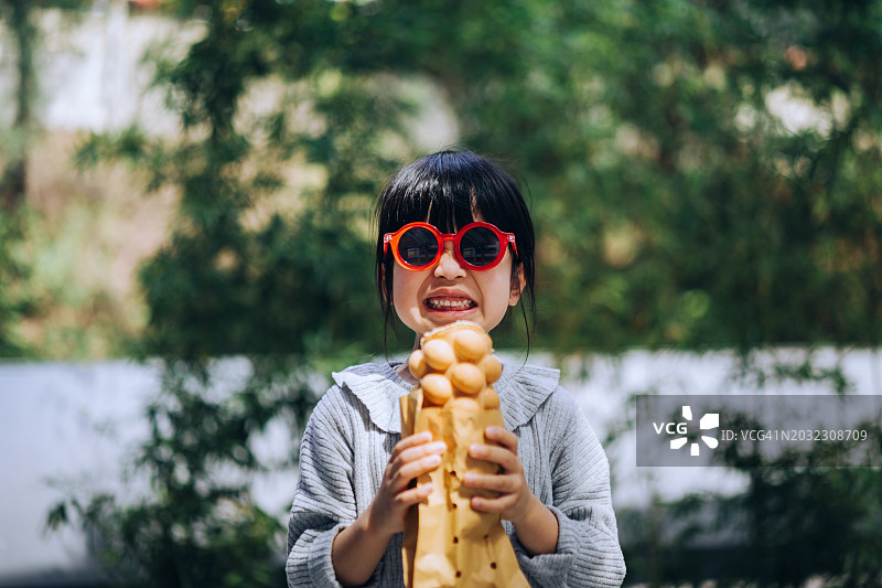 在香港街头品尝鸡蛋仔的可爱亚洲小女孩图片素材
