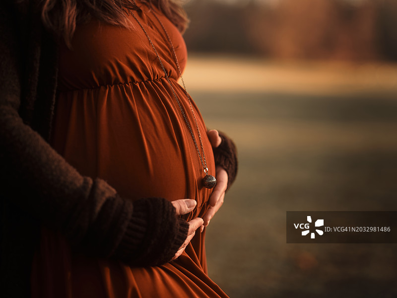 孕妇站立，双手抚摸腹部的中段图片素材