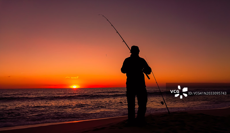 日落时分，男子在海滩钓鱼的剪影图片素材