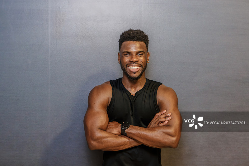 微笑男人抱臂墙前拍照图片素材
