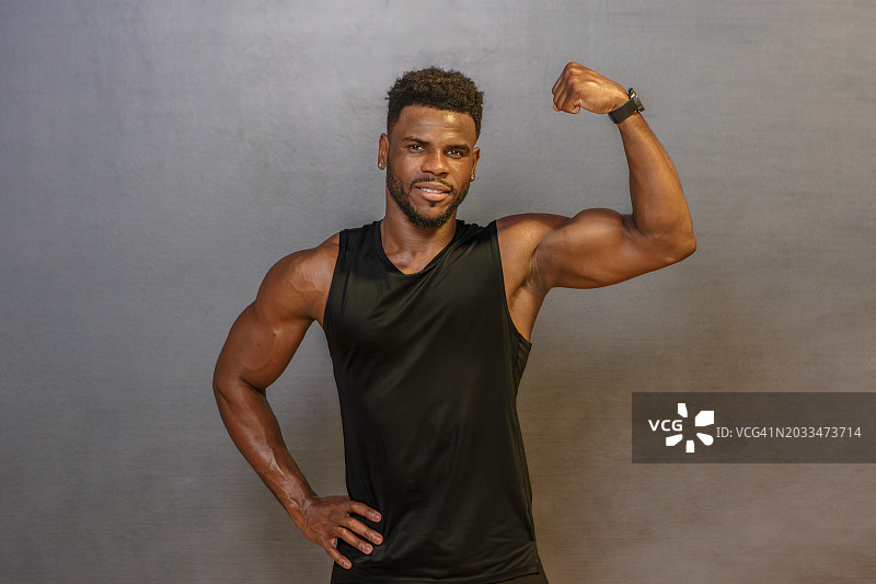 男人在灰色墙前展示肱二头肌图片素材