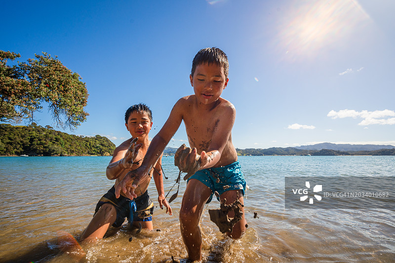 孩子们在海滩玩泥巴，玩得很开心。图片素材