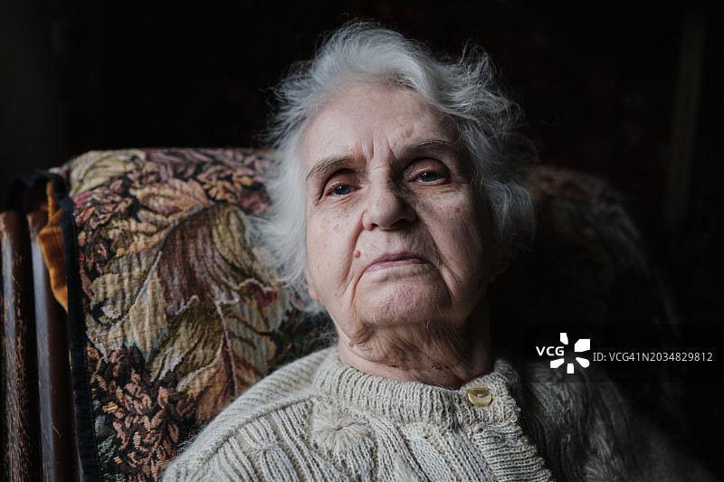 悲伤沮丧的年长妇女坐在扶手椅上图片素材